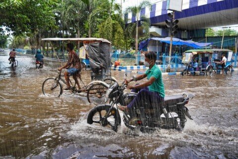 Commuters riding through a waterlogged street during Kolkata's monsoon season