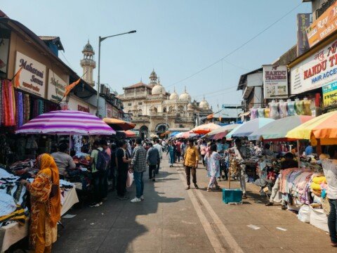 Narrow, crowded wholesale market lane lined with textile and trading shops, similar to Burrabazar in Kolkata