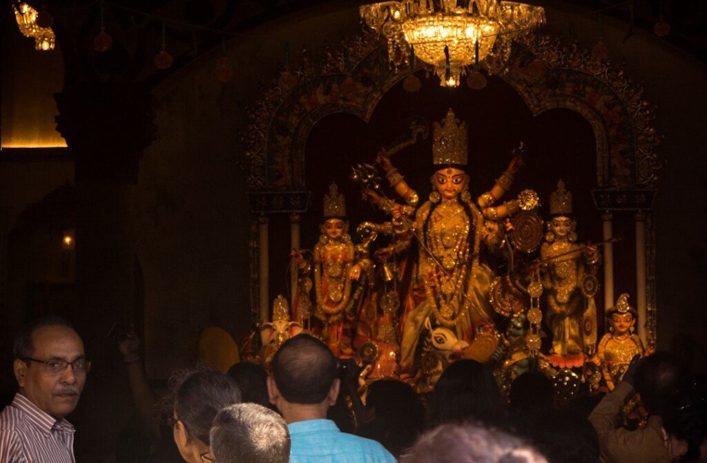 Illuminated Durga Puja pandal crowded with visitors at night in Kolkata