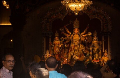 Illuminated Durga Puja pandal crowded with visitors at night in Kolkata