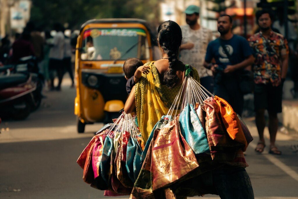 Shopper carrying colorful bags along a busy street market in North Kolkata near Hatibagan
