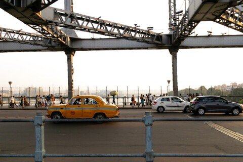 Traffic including taxis crossing near Howrah Bridge in Kolkata, illustrating the city's mix of transport options