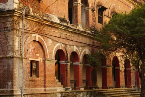 Historic brick building with arched corridors on a Kolkata university campus