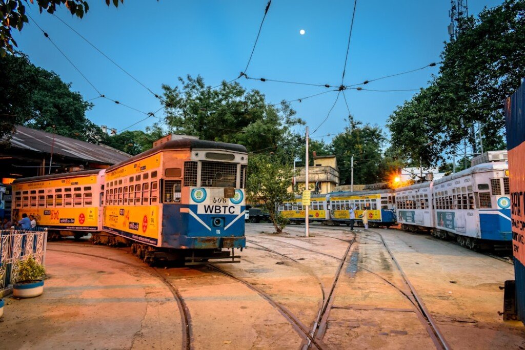 Yellow and white Kolkata tram running on a city street, one of the last operating tram routes in India