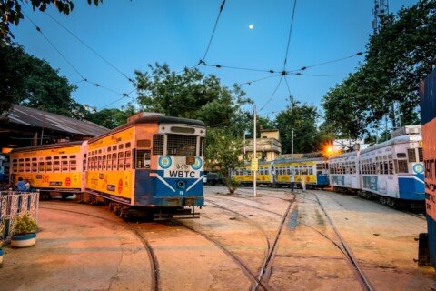 Yellow and white Kolkata tram running on a city street, one of the last operating tram routes in India