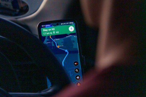 Commuter checking a navigation app on a smartphone while planning a route through Kolkata traffic