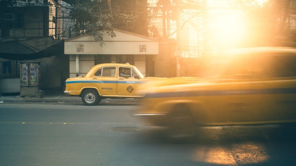 Classic yellow taxi driving on a Kolkata street, used for the auto and taxi fare guide