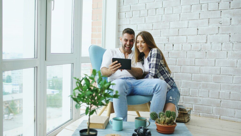 Couple happily looking at tablet together on tablet.