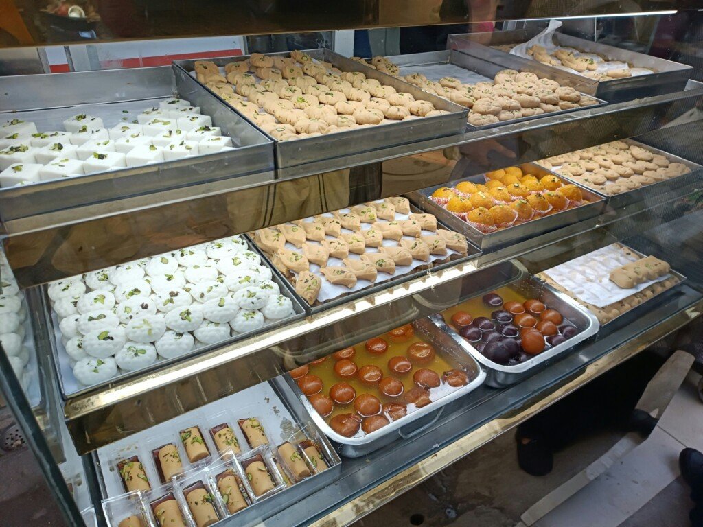 Glass bakery display case filled with cakes, pastries and puffs of the kind sold at bakeries in Kolkata