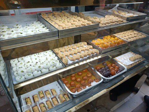 Glass bakery display case filled with cakes, pastries and puffs of the kind sold at bakeries in Kolkata