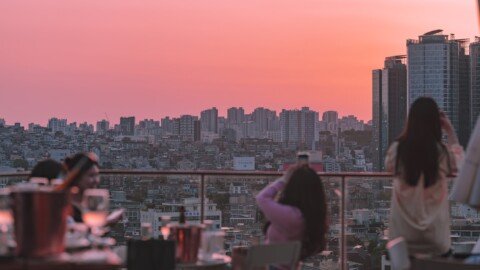 People enjoying sunset views from a rooftop restaurant terrace over a city skyline, similar to Kolkata's rooftop dining spots