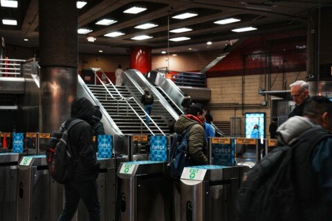 Commuters passing through subway turnstile gates with smart cards, illustrating the Kolkata Metro ticket and card system
