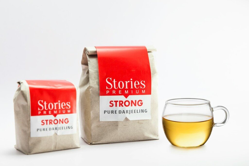 Two packets of Darjeeling loose-leaf tea beside a cup of tea, one of the most popular Kolkata souvenirs to take home