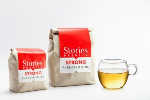 Two packets of Darjeeling loose-leaf tea beside a cup of tea, one of the most popular Kolkata souvenirs to take home