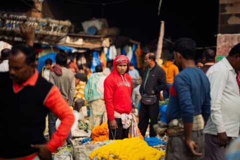 Shoppers crowd a colourful street market lane in Kolkata lined with clothing and accessory stalls, typical of Esplanade street shopping