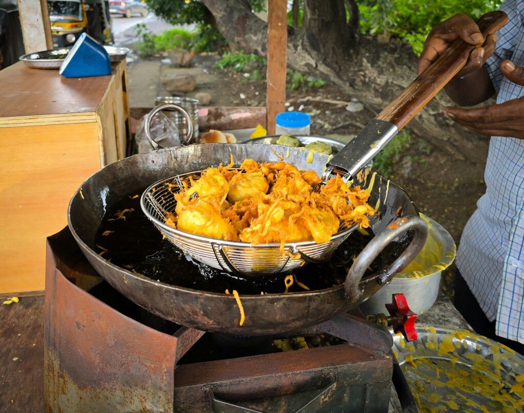 Fresh fritters being deep fried in hot oil at an Indian street food stall