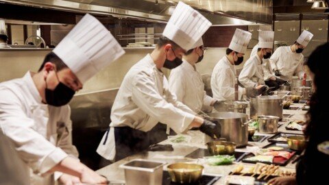 Best Hotel Management Colleges in Kolkata: IHM Taratala, IIHM, GNIHM Fees & Admission 28 Trainee chefs in white uniforms working in a professional hotel kitchen, representing hotel management colleges in Kolkata