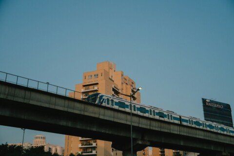 Metro train running on an elevated viaduct, similar to the Kolkata Metro Orange Line along the EM Bypass