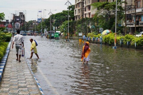 People walking through a flooded city street during heavy monsoon rain