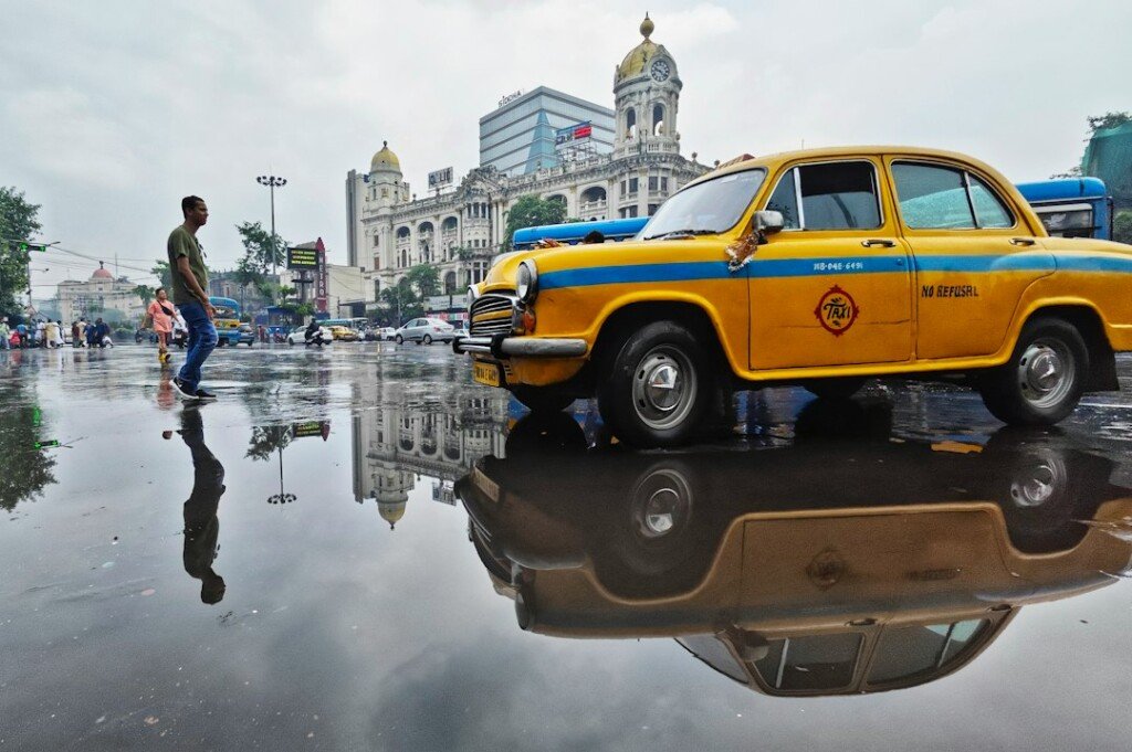 Yellow Kolkata taxi on a rain soaked street after heavy monsoon rain, September 2026
