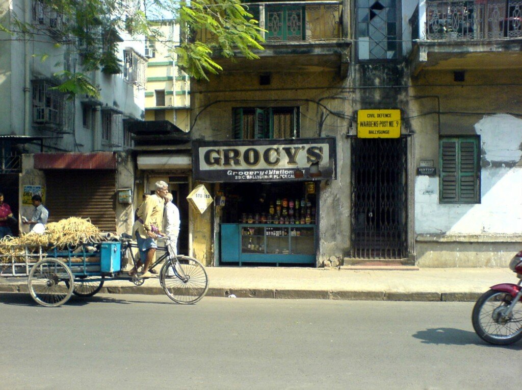 A busy street scene in Kolkata, West Bengal, with shops and signboards