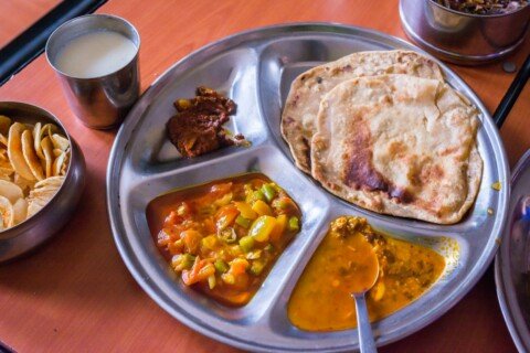 A spread of Mughlai food with mutton curry, kebabs and Indian breads served on a round tray, typical of Kolkata's Mughlai restaurants