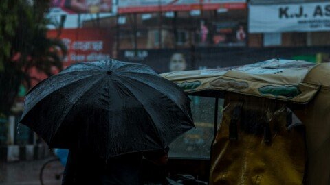 People walking with umbrellas through heavy monsoon rain on a city street