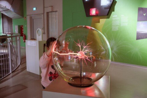 A child touching a plasma ball at a hands-on science exhibit, similar to the interactive displays in Dynamotion Hall at Science City Kolkata