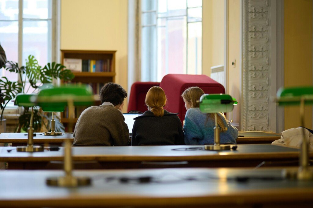 Three students sitting at desks studying in a university library