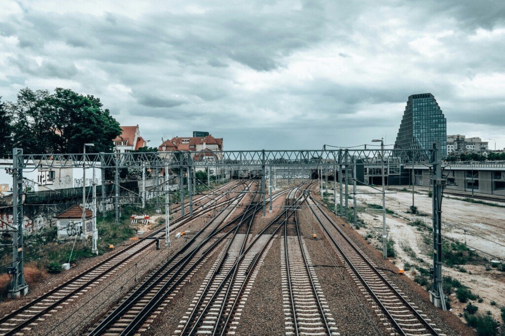 Railway tracks curving past city buildings, similar to the approach into a busy suburban terminus