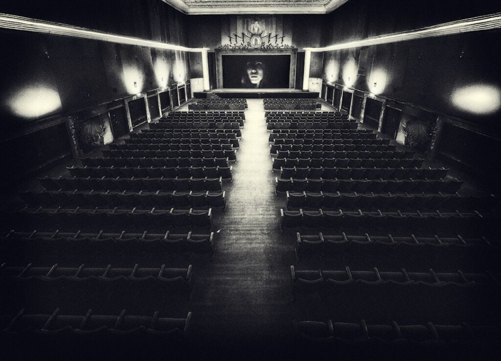 Empty vintage cinema hall with rows of seats facing a lit screen