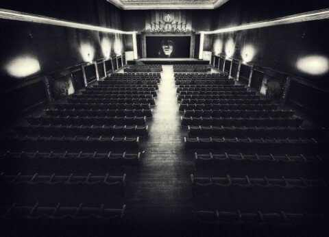 Empty vintage cinema hall with rows of seats facing a lit screen