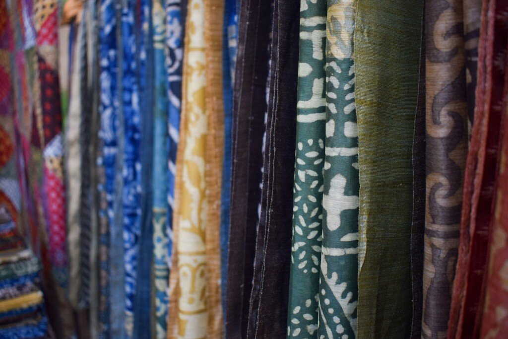 Rows of brightly coloured sarees and wedding fabrics hanging on display at a market shop, typical of wedding shopping in Kolkata