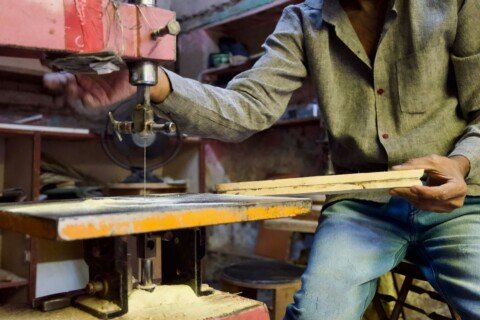 Carpenter cutting timber in a wooden furniture workshop, similar to the maker-run furniture shops along BB Ganguly Street in Bowbazar, Kolkata