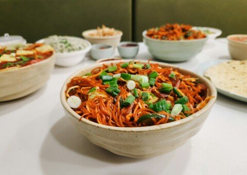 Wok-tossed Indo-Chinese Schezwan noodles with vegetables in a spicy red sauce