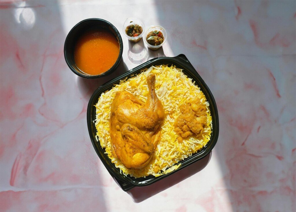 Plate of chicken biryani with rice and sauce, representing Kolkata biryani