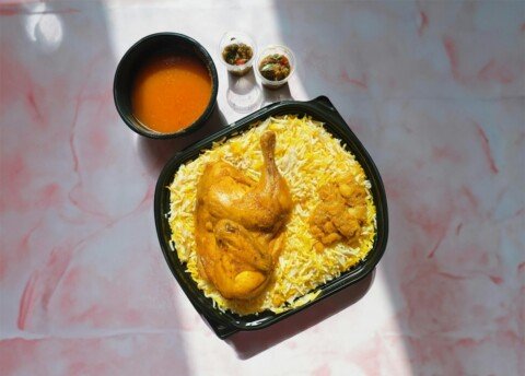 Plate of chicken biryani with rice and sauce, representing Kolkata biryani