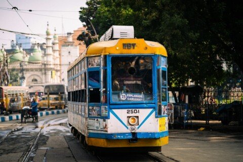 Yellow and blue public transport vehicle on a busy Kolkata city street