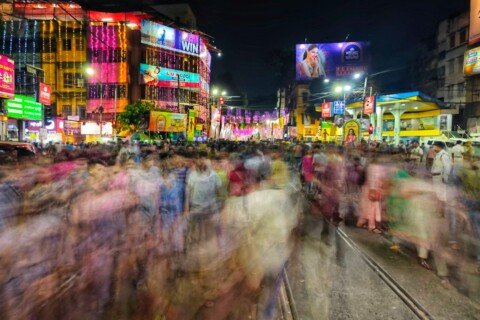 Crowd walking along a busy Kolkata street at night with evening lights