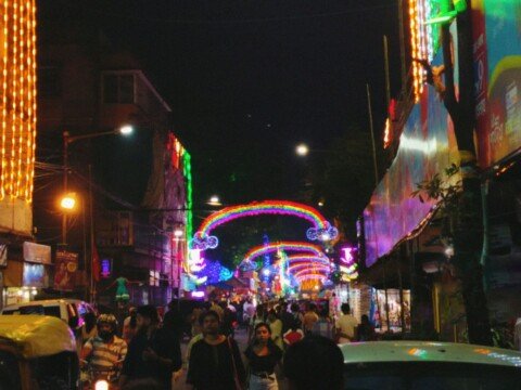 People walking along a lit city street at night in Kolkata, near restaurants and cafes