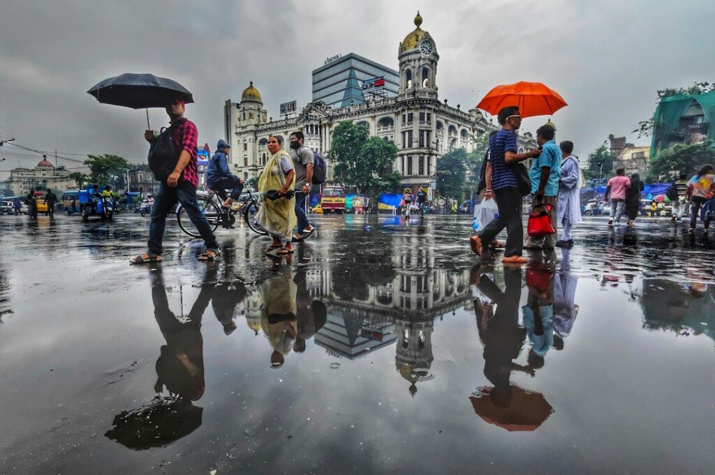 A group of people walking down a street holding umbrellas in the rain