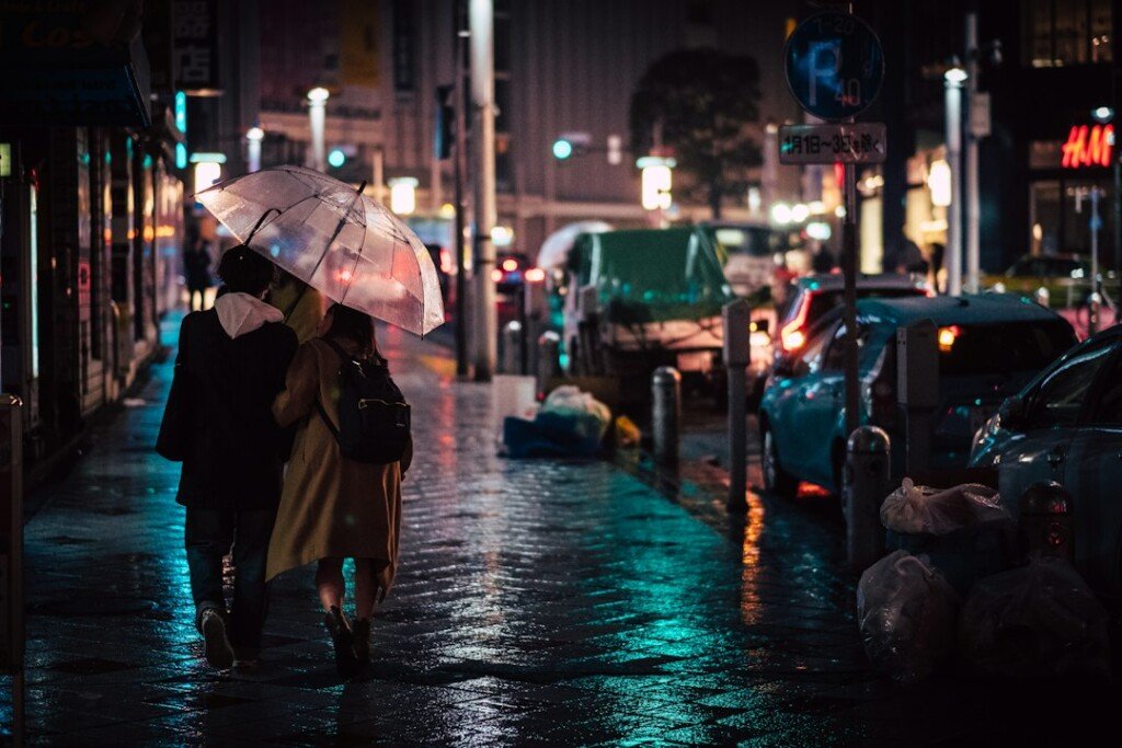People holding umbrellas walking on a wet road in the rain