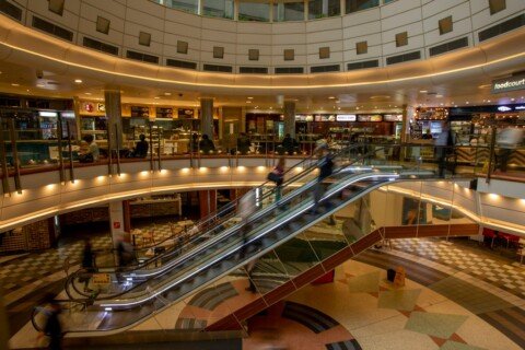 Shoppers on an escalator inside a large shopping mall