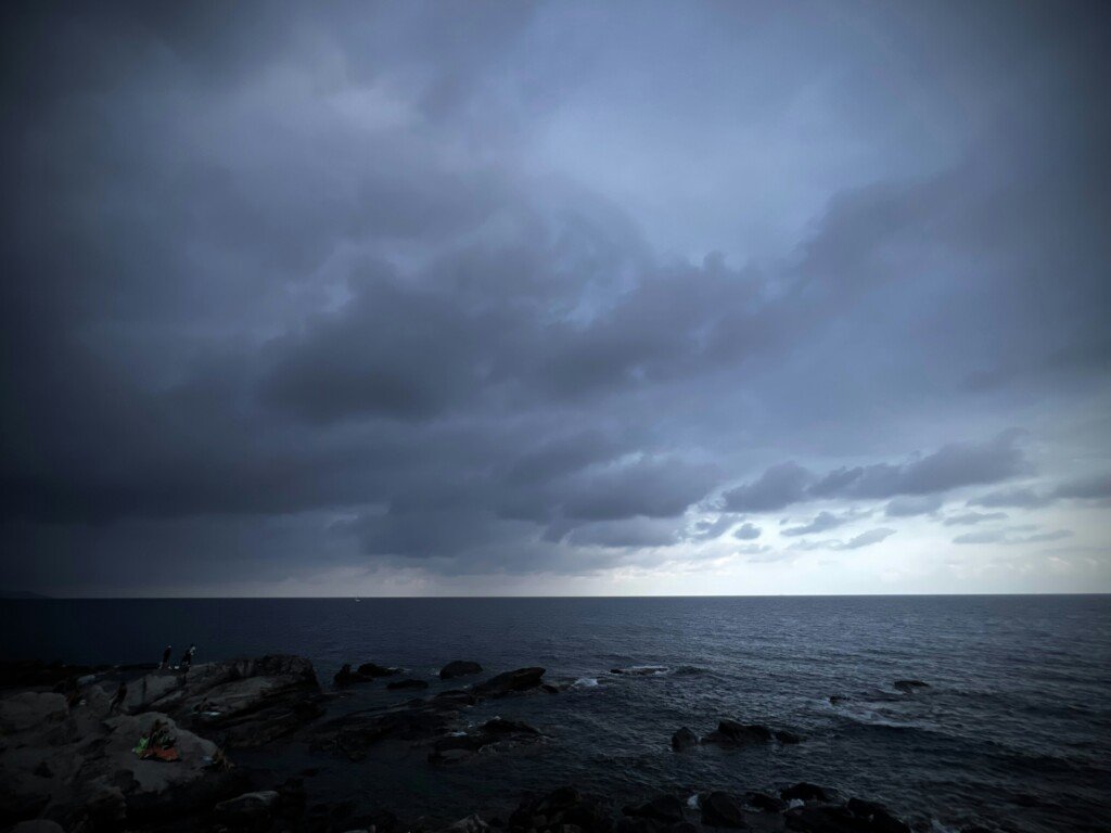 Dark storm clouds over a moody ocean and rocky coast ahead of Cyclone Arnab
