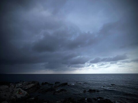 Dark storm clouds over a moody ocean and rocky coast ahead of Cyclone Arnab