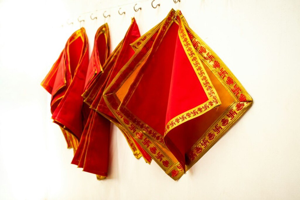 Folded handwoven Bengali saree with a crimson border and gold detail
