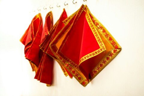 Folded handwoven Bengali saree with a crimson border and gold detail