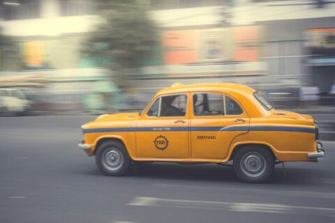 Yellow Kolkata taxi driving past Chandni Chowk, illustrating auto and taxi fares in the city